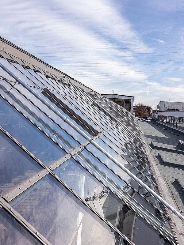 Nahaufnahme des Glasdachs des Factory Campus Düsseldorf mit reflektierendem Himmel und moderner Architektur.