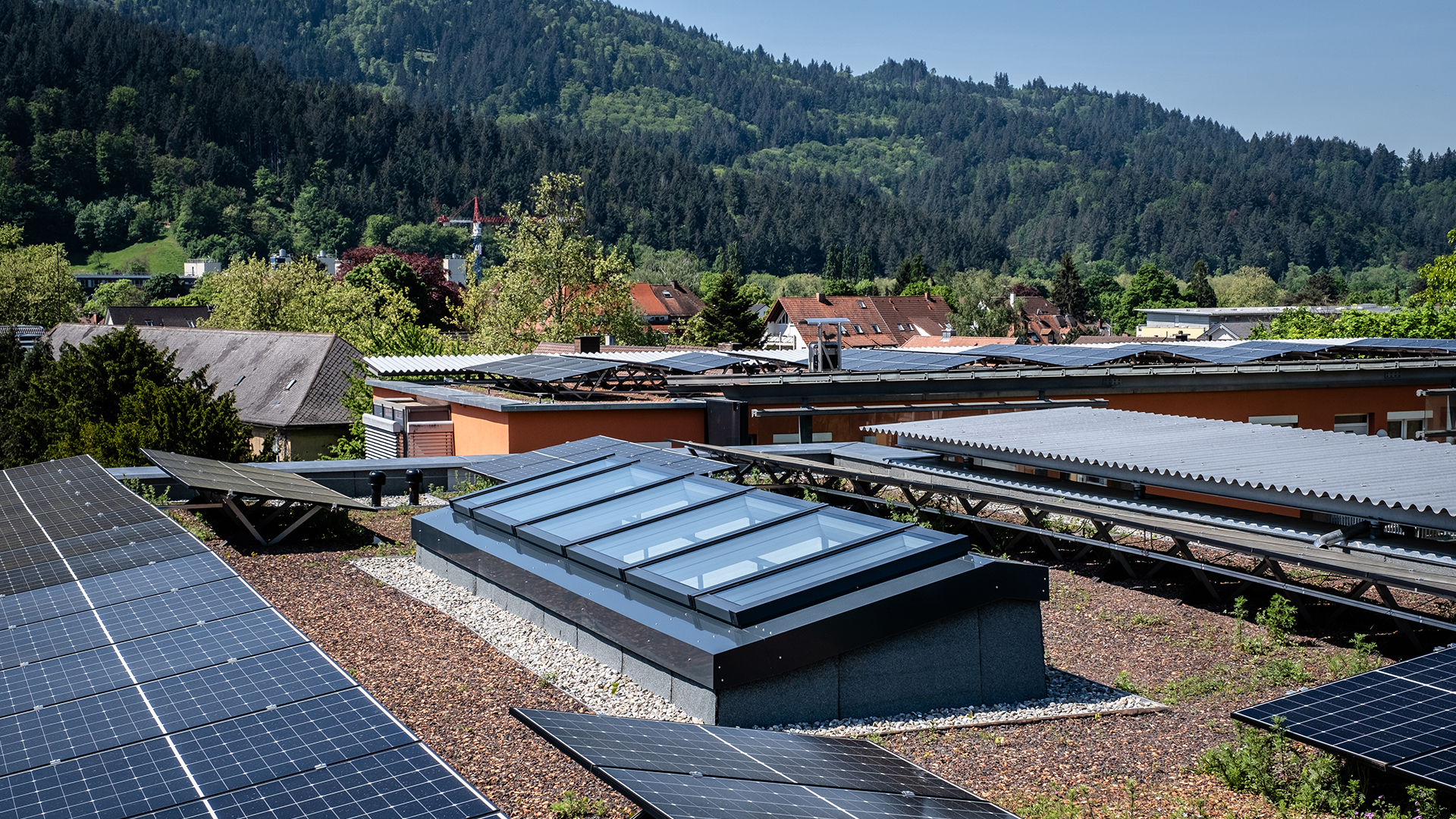 Modulares Glasdach von LAMILUX auf einem Wohnhaus in Freiburg, umgeben von Solarpanelen und einer grüner Landschaft.